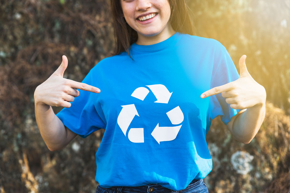 Dziewczyna pokazująca na koszulkę z logo recyklingu